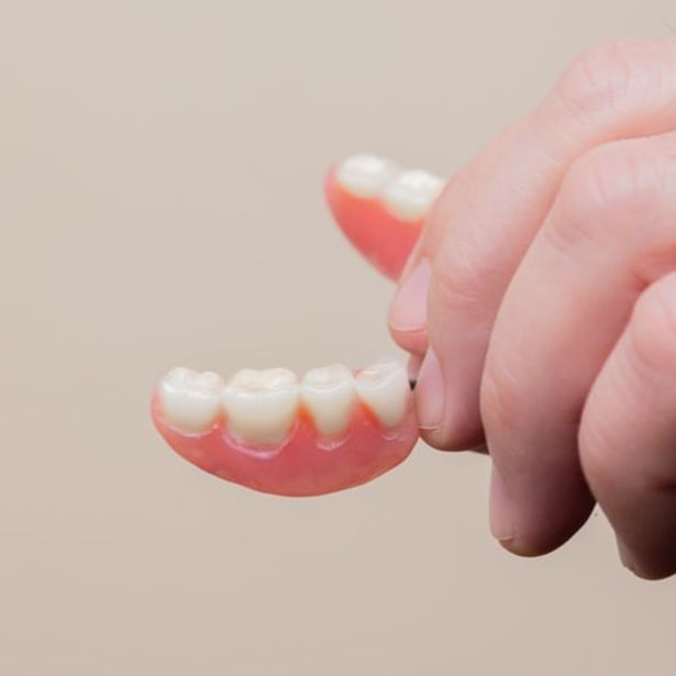 Complete denture being held by a hand